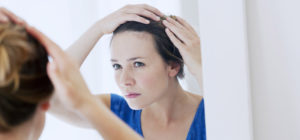 woman checking hairline for hair loss